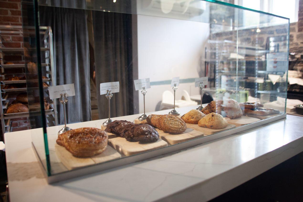 Pastries and croissants under glass at a café.