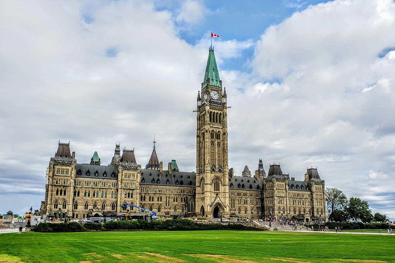 A grassy slope on Parliament Hill with the Houses of Parliament and the Peace Tower in the background.