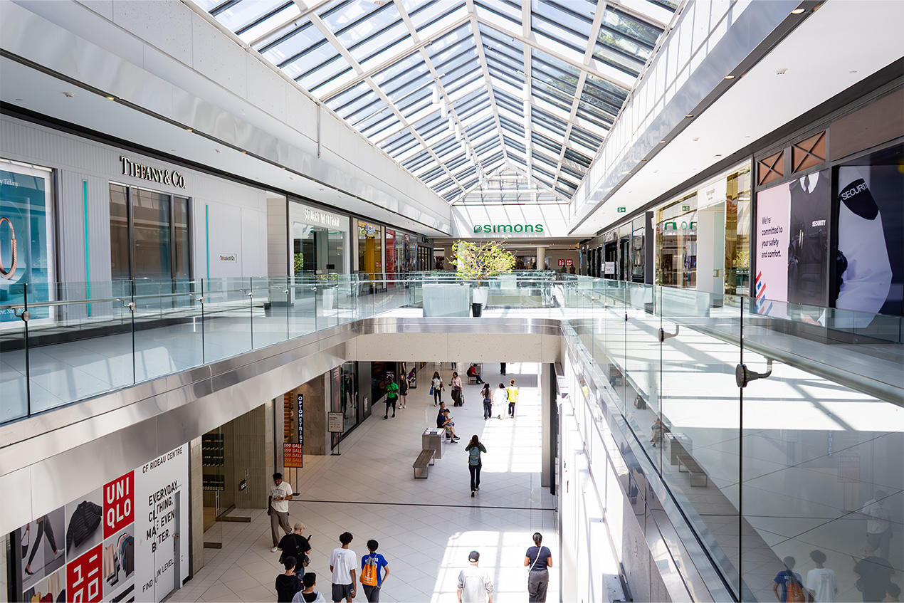 Two floors of shops under a triangular glass roof at the Rideau Centre.