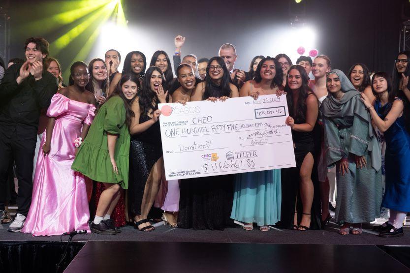 Student members of CASCO hold up a giant cheque showing money raised for CHEO.