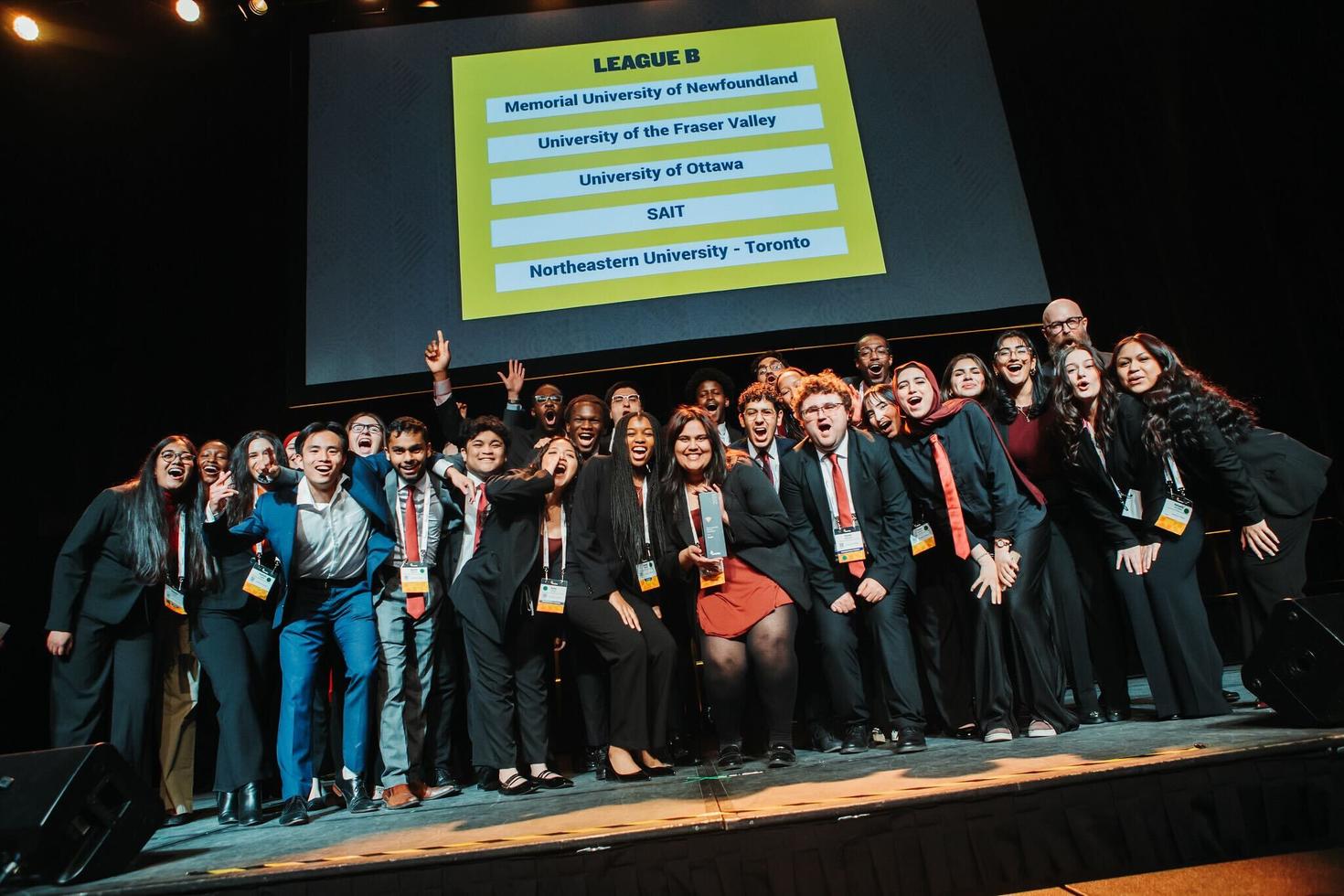 A large group of students from the uOttawa Enactus team on stage at a competition with other universities.