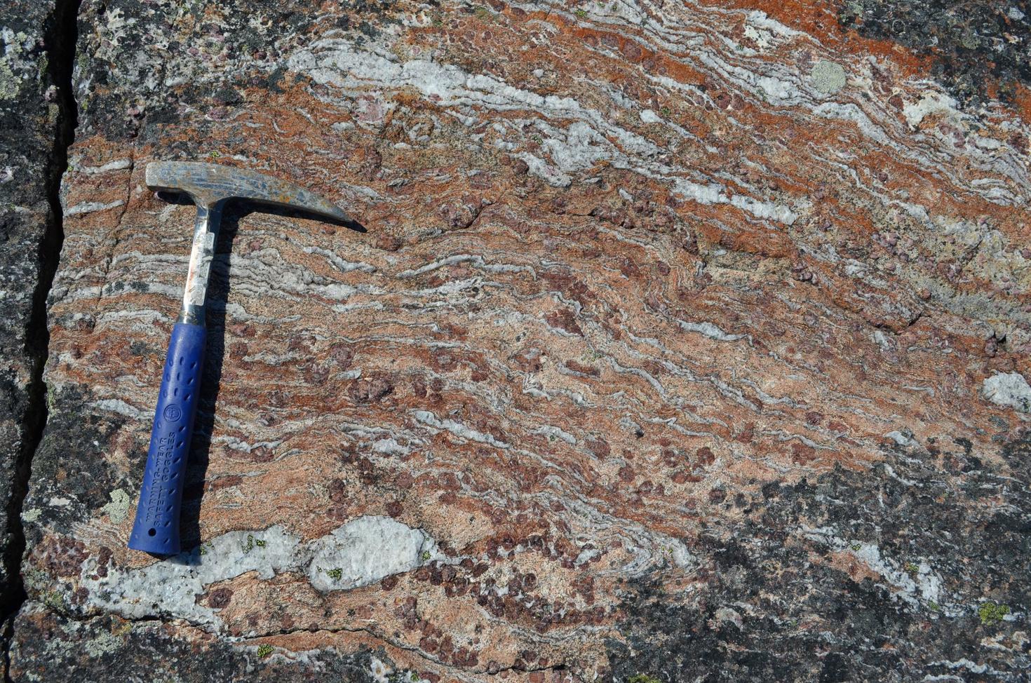 Close-up of an ancient, layered rock formation known as the Ujaraaluk unit. The name Ujaraaluk means “old solid rock” in Inuktitut. These rocks, believed to be 4.3 billion years old, display bands of reddish and grey minerals. 