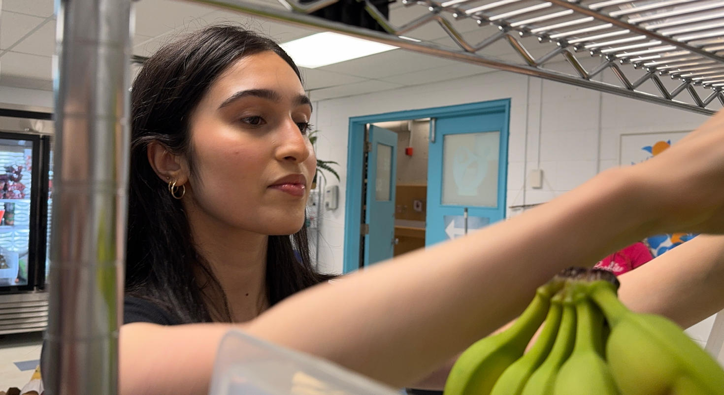 Aleezah Sumaiya Shaikh, étudiante bénévole, empile des bananes sur des étagères à la banque alimentaire du syndicat étudiant de l'Université d'Ottawa.
