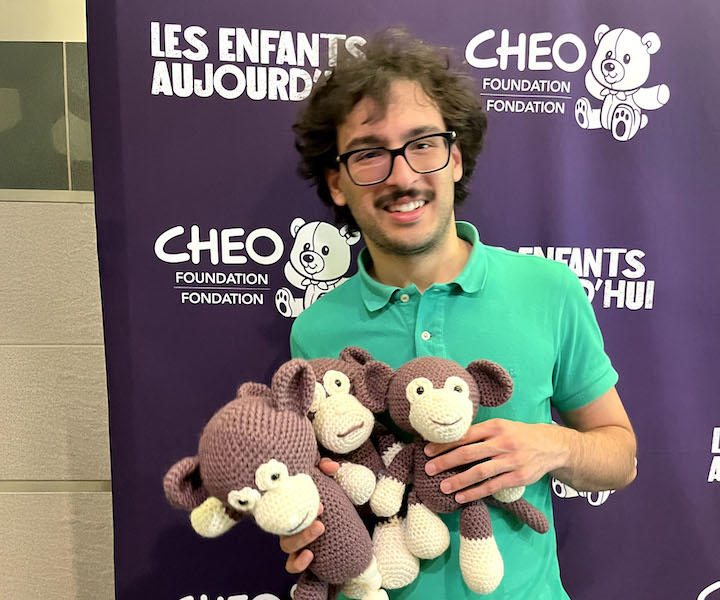 a medical student holding three crocheted monkeys.