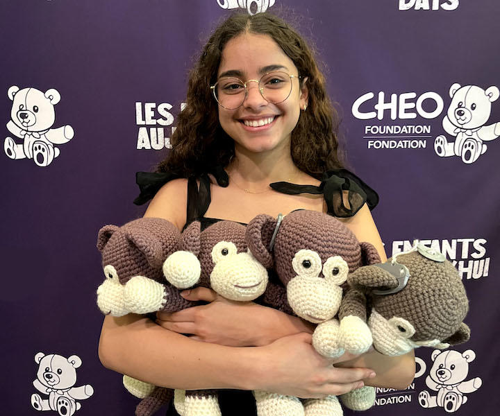 a medical student holding 4 crocheted monkeys.