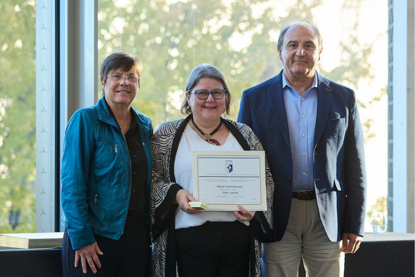 Dr. Melissa Brouwers holding a certificate alongside two leaders of the CAHS.