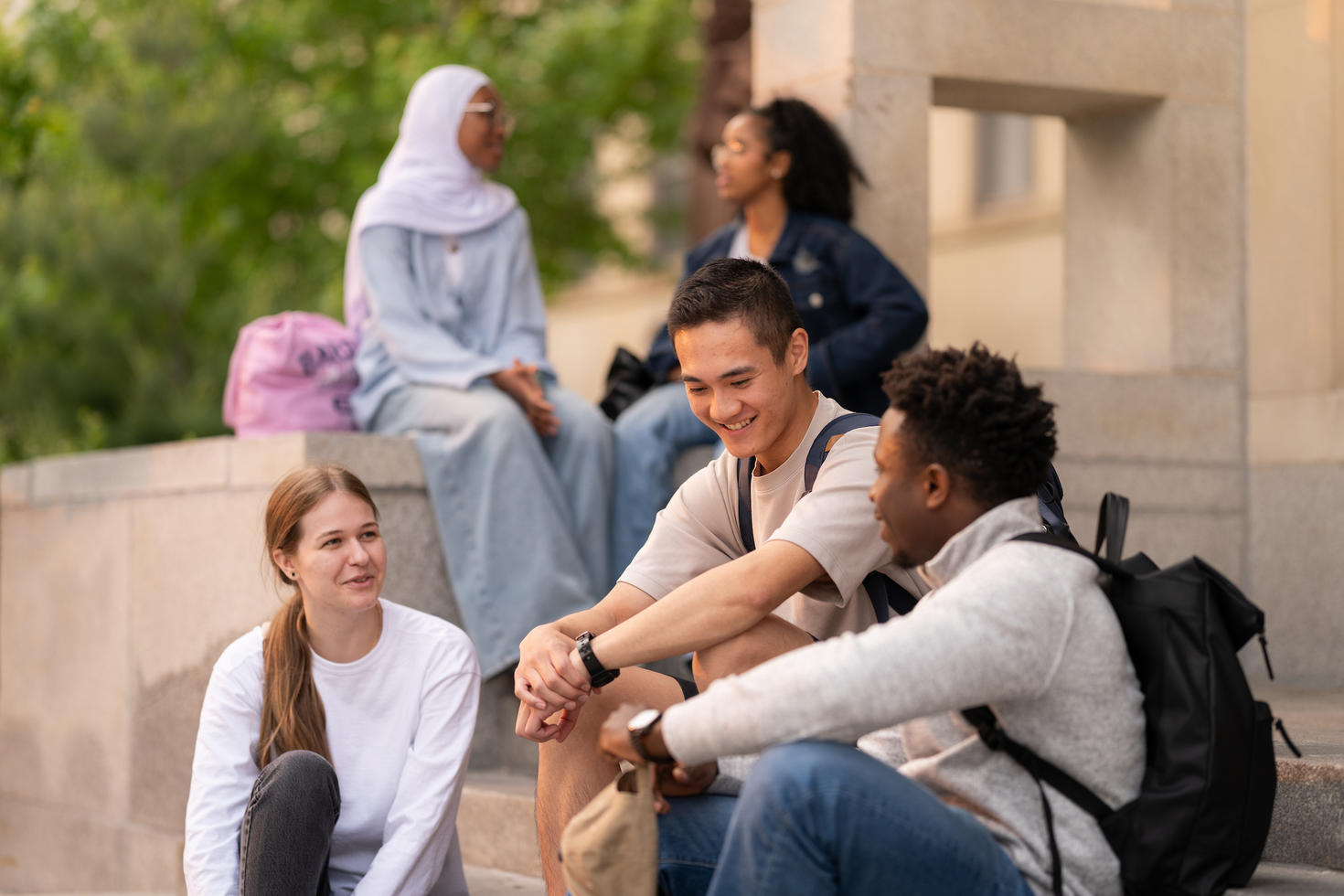 Students sitting and chatting outside campus building. 