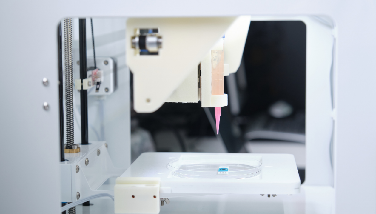Close-up of a 3D bioprinter depositing bio-ink into a petri dish.