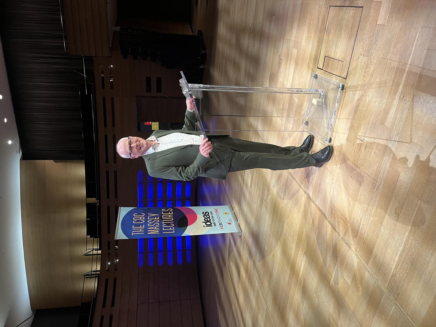 Alex Neve at the podium, on stage at the CBC Massey Lecture