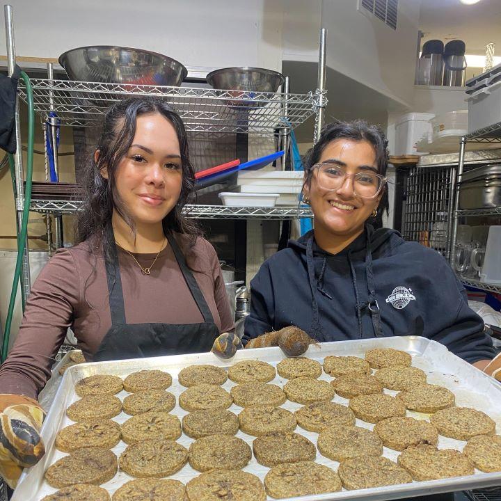 Adrianna Ermacora and Divika Solanki show a tray of freshly-baked, high-nutrient cookies.