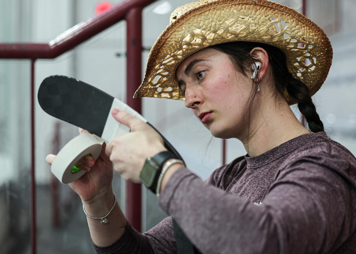 Gee-Gees women's hockey player taping her hockey stick with a cowboy hat on