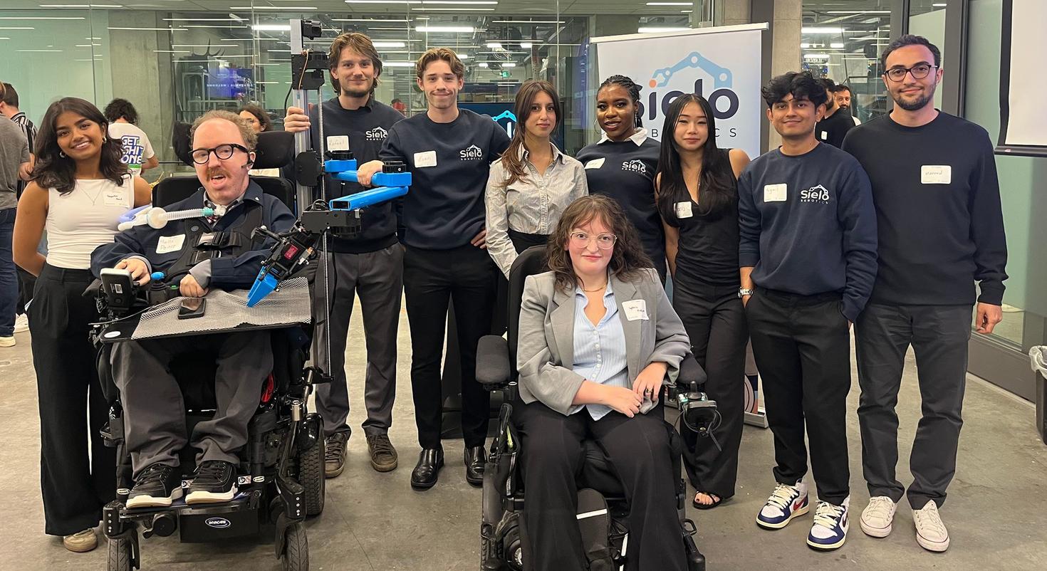 Un groupe d'étudiants membres de l'équipe Sielo Robotics avec deux conseillers en fauteuils roulants motorisés.