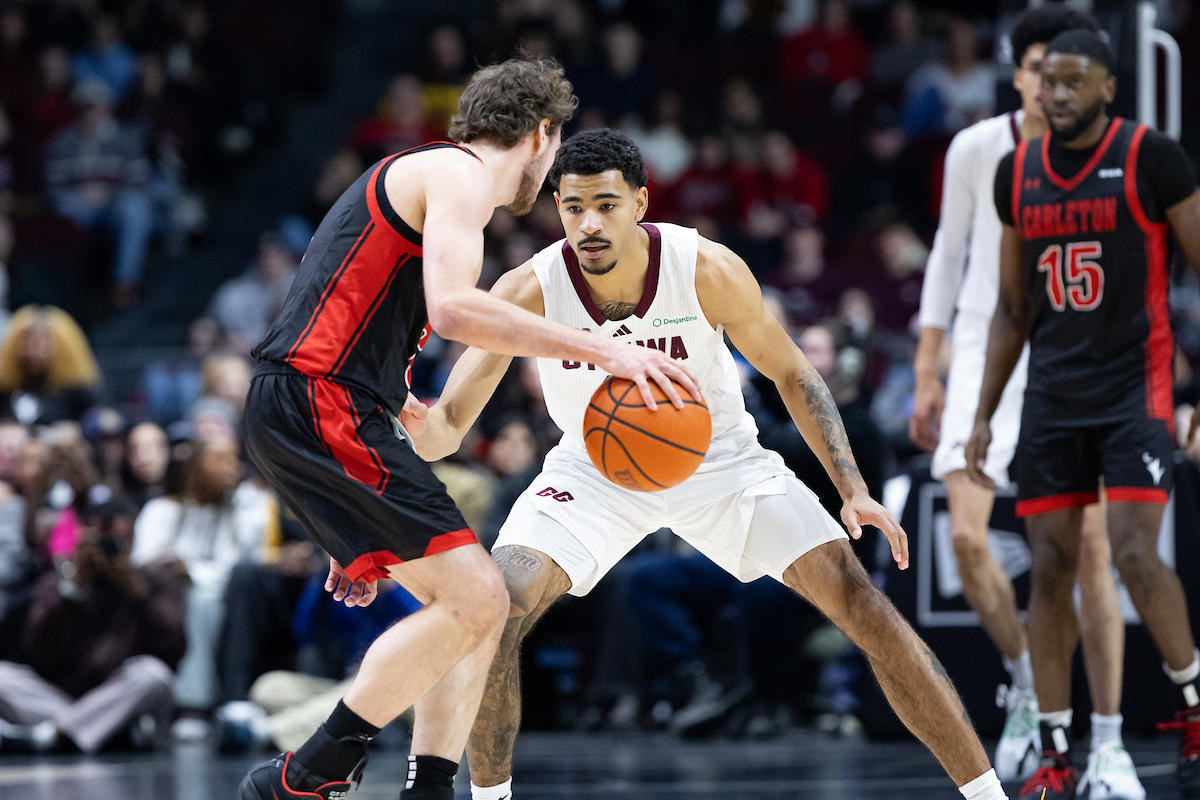 Gee-Gees men's basketball player facing the Carleton Ravens men's basketball player who is in possession of the ball