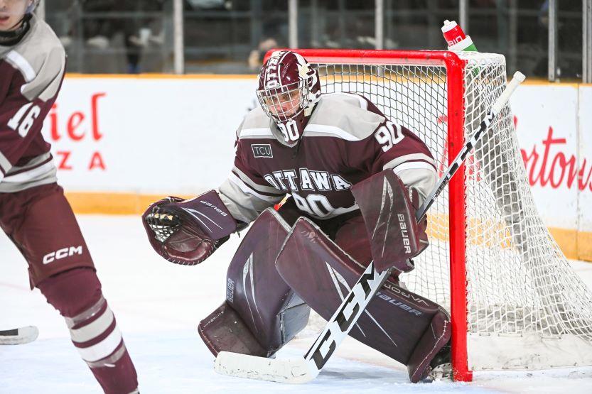 Le gardien de but masculin des Gee Gees, Franky Lapenna, s'accroupit devant le filet, prêt à arrêter un tir.