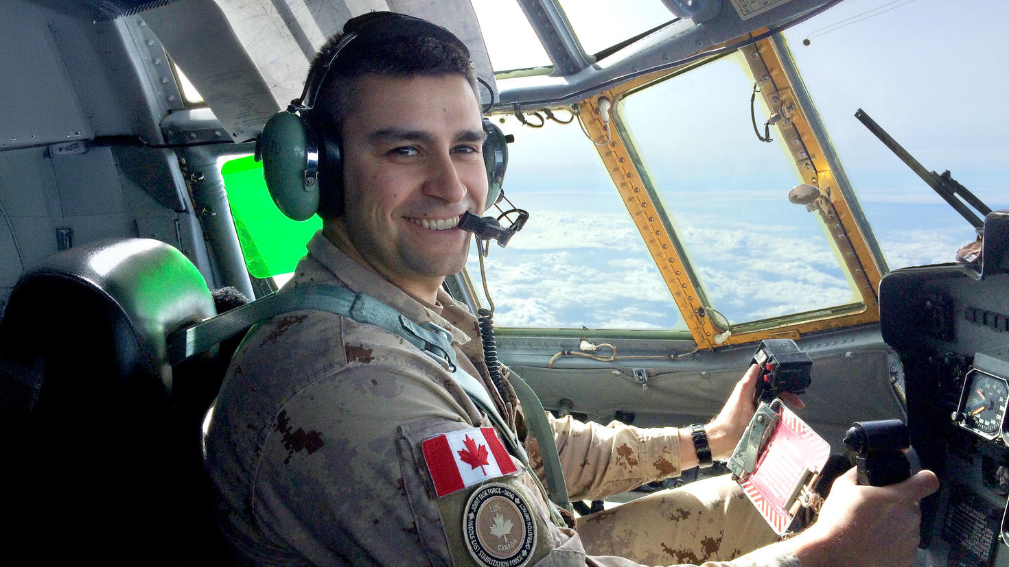 A person sitting in the cockpit of a plane in a military uniform.