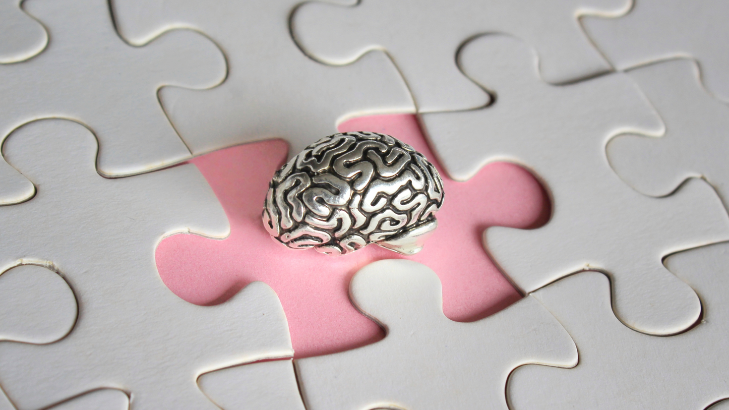 Small metal brain on a puzzle.