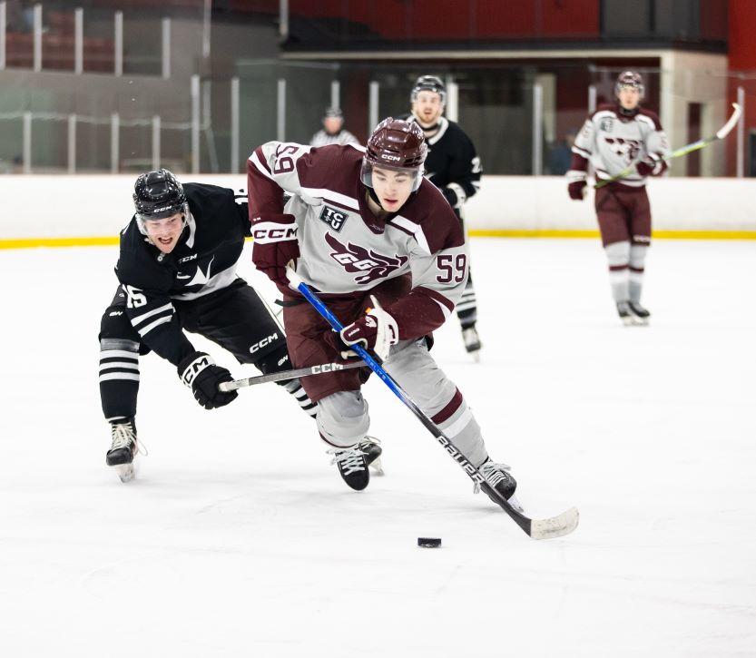 Mitchell Martin, joueur de l'équipe masculine de hockey des Gee Gees, dribble avec le palet autour des joueurs adverses.