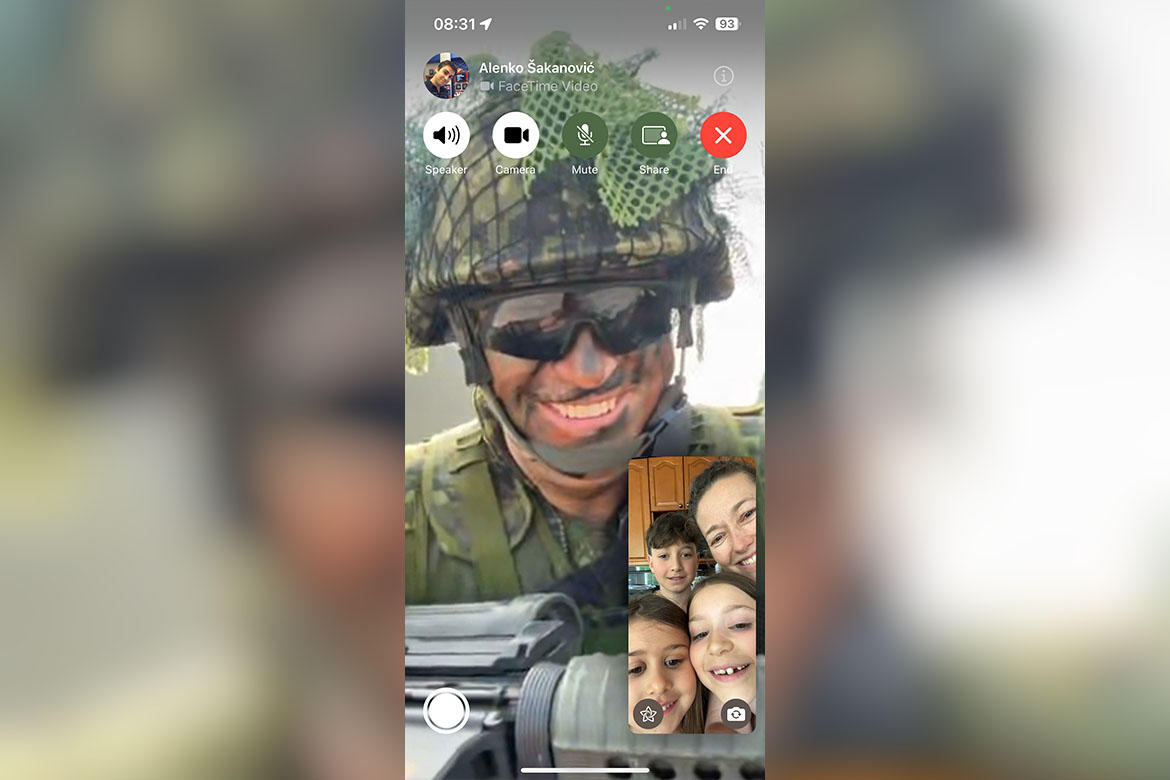 a person in a military uniform enjoying a FaceTime call with members of their family.