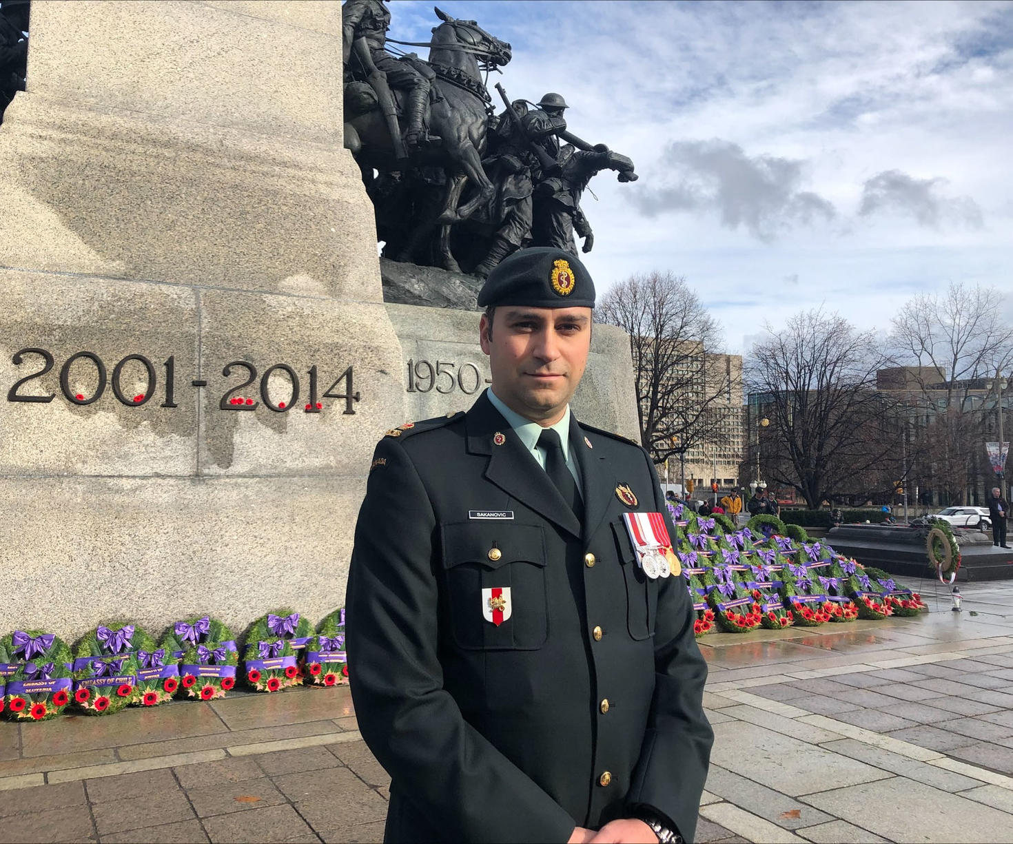 Un major des Forces armées canadiennes se tient devant le Monument commémoratif de guerre du Canada.