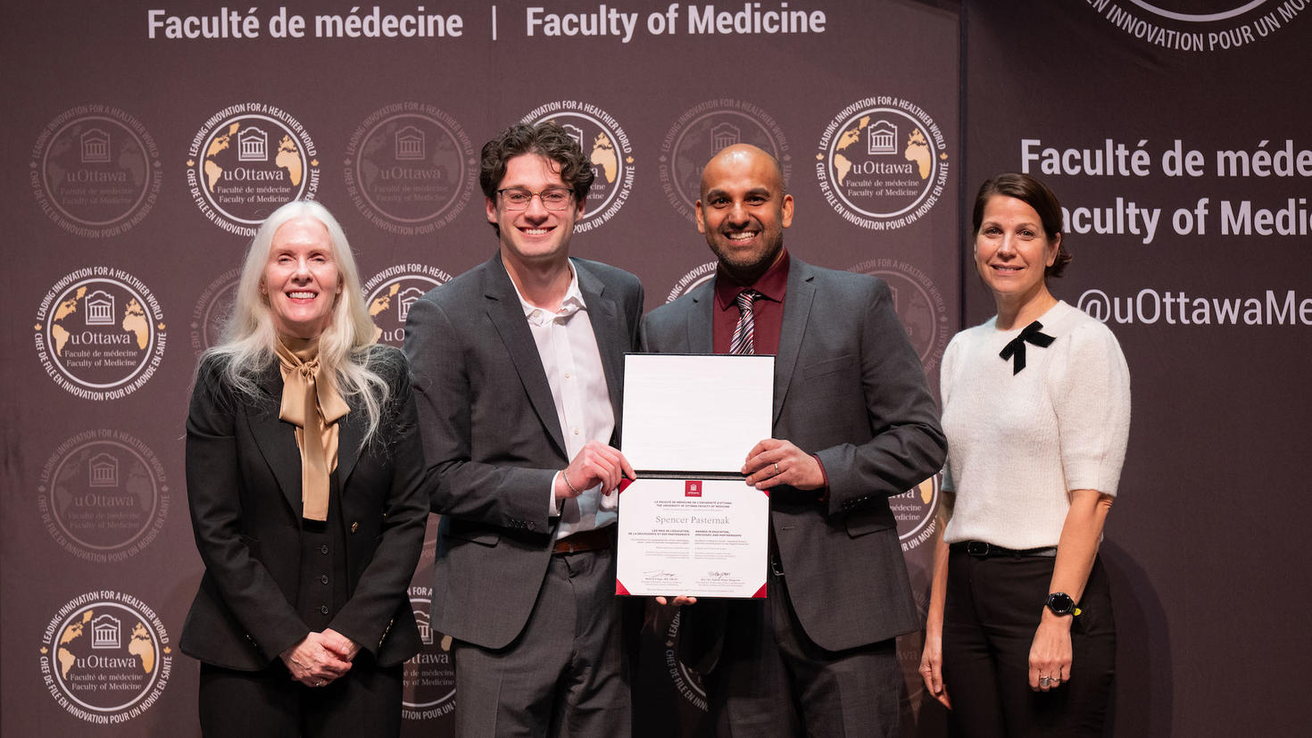 Une personne lauréate pose avec un certificat aux côtés de trois membres du corps professoral.