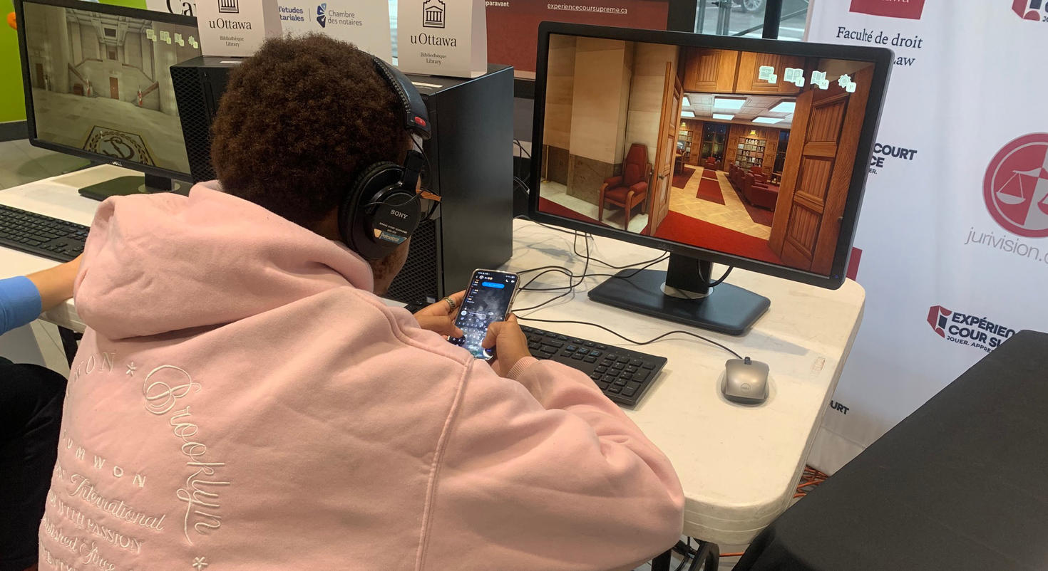Un étudiant joue au jeu « Supreme Court Experience ». Un écran d'ordinateur montre l'intérieur d'une salle d'audience.