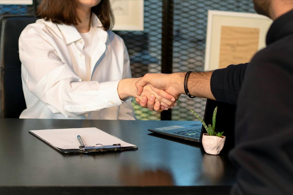 Woman and man at desk shaking hands