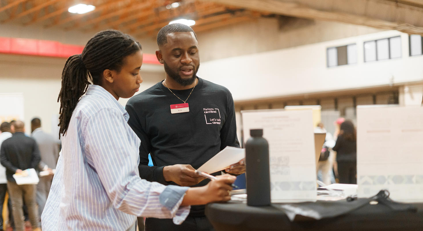 Une étudiante et un étudiant lisent des documents à une table lors de la Semaine des carrières de l'année dernière.