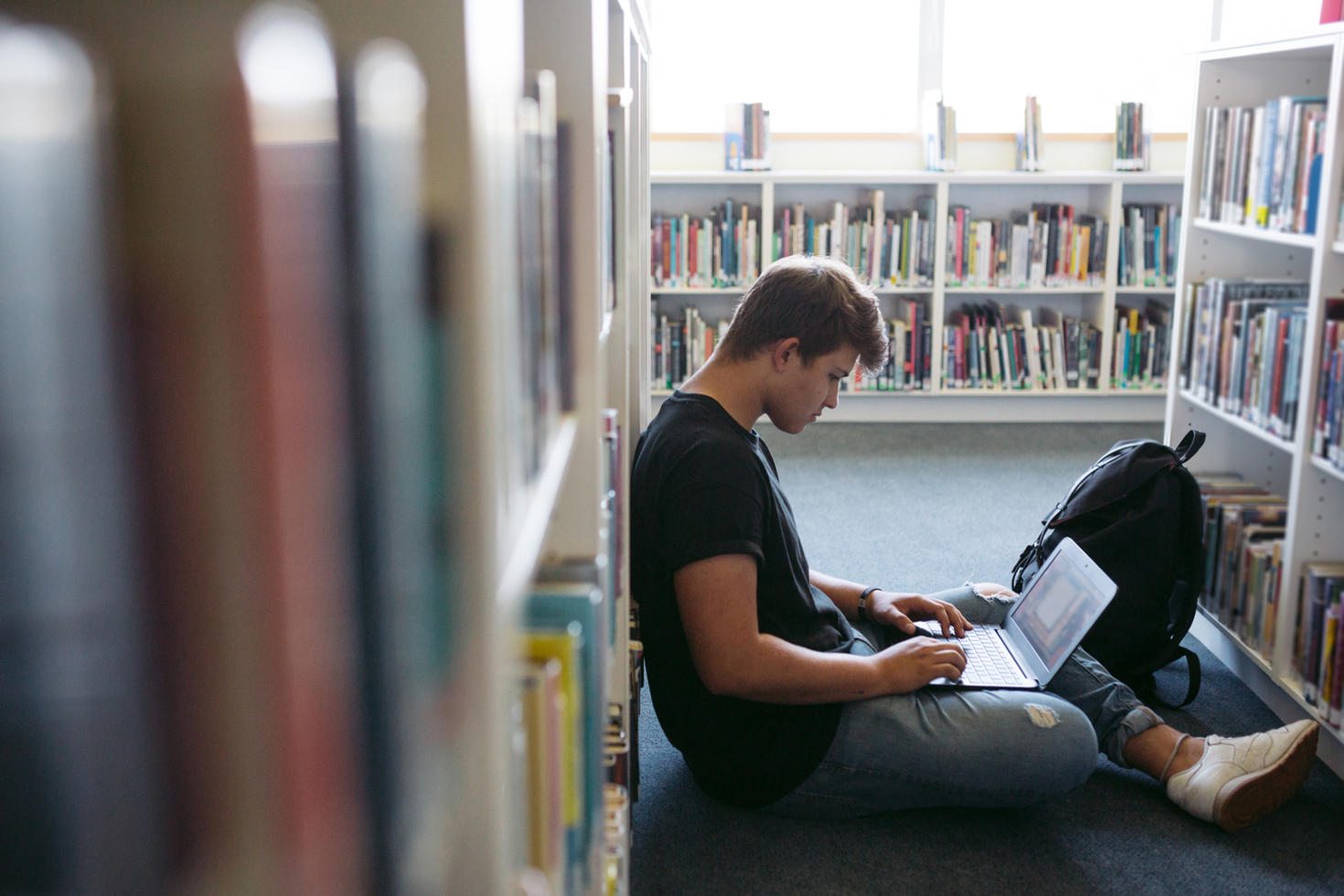 Étudiant sur le plancher dans la bibliothèque