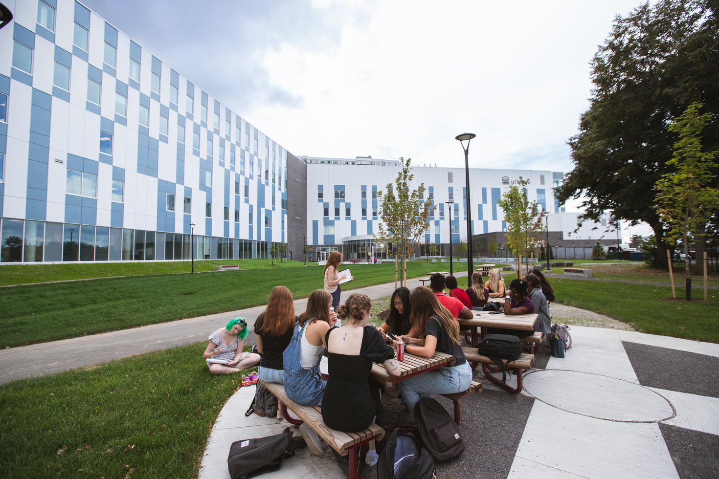 Des étudiants de l'Université d'Ottawa assis à une table de pique-nique devant le bâtiment de la Faculté des sciences de la santé.