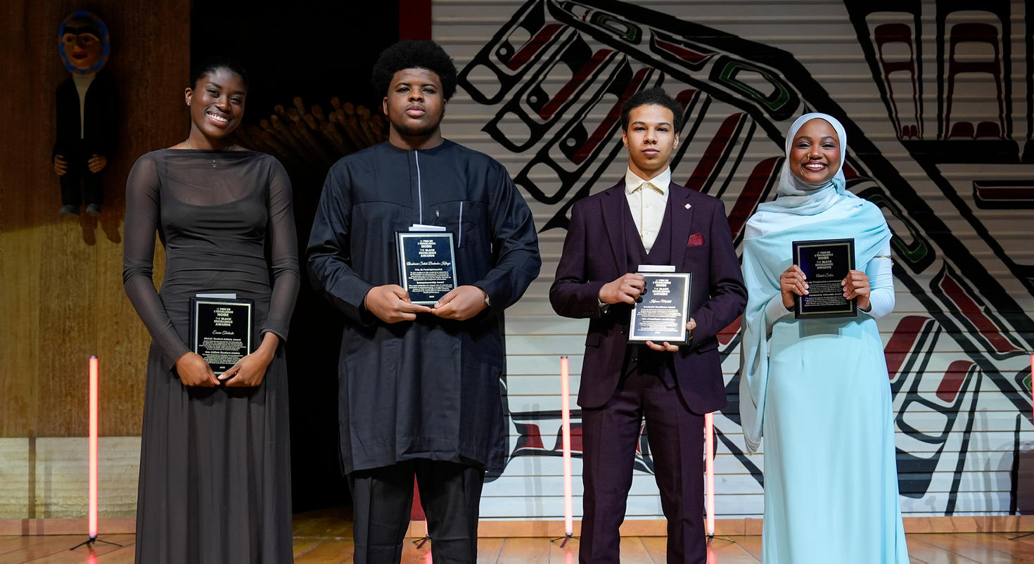 Les quatre lauréats du Prix de l’excellence noire 2026 se tiennent côte à côte sur scène, tenant fièrement leurs plaques commémoratives.