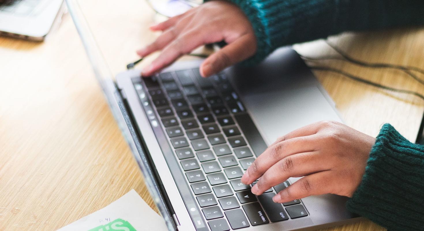Deux mains tapant sur le clavier d'un ordinateur portable.