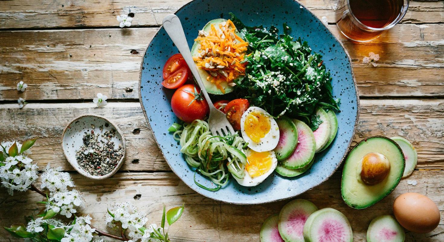 A bowl of healthy salad that includes tomatoes, avocado, boiled eggs and garnishes.