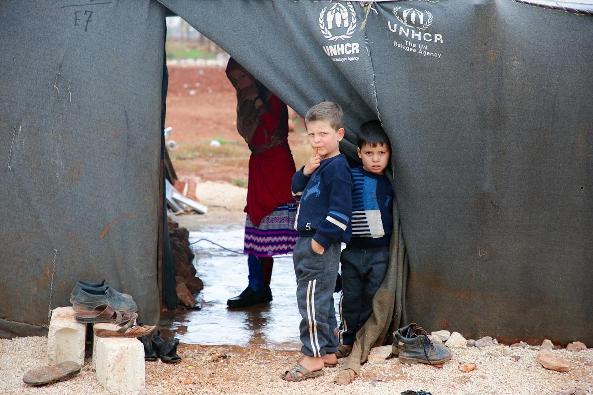 Two boys peak out from a UNHCR tent