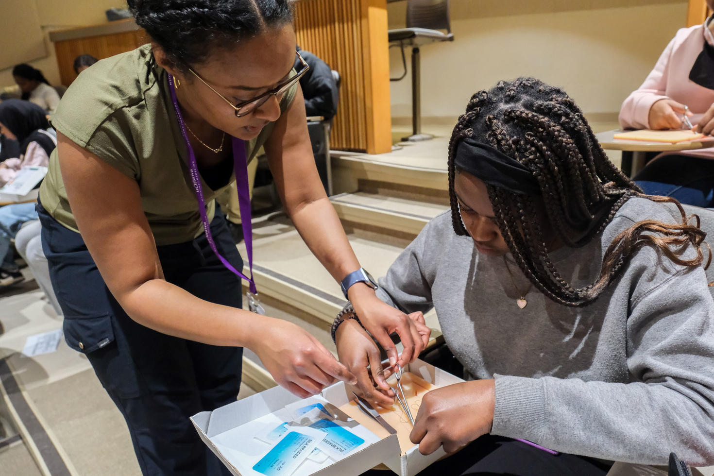 a health professional helping a student practice suturing techniques