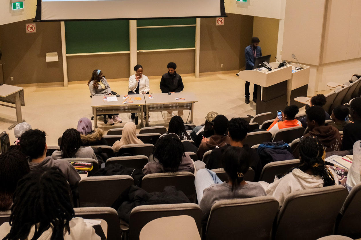 A panel of experts seated in front of an amphitheatre full of students.