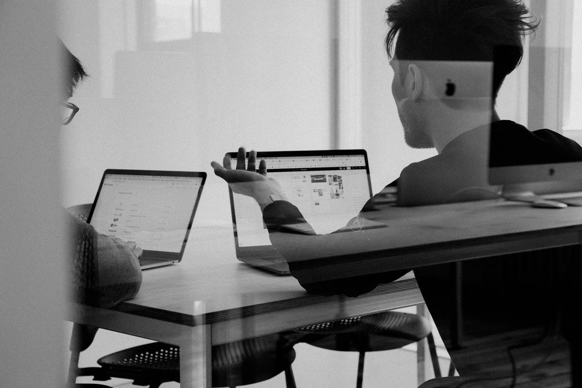 Pair of people sitting at table on laptops