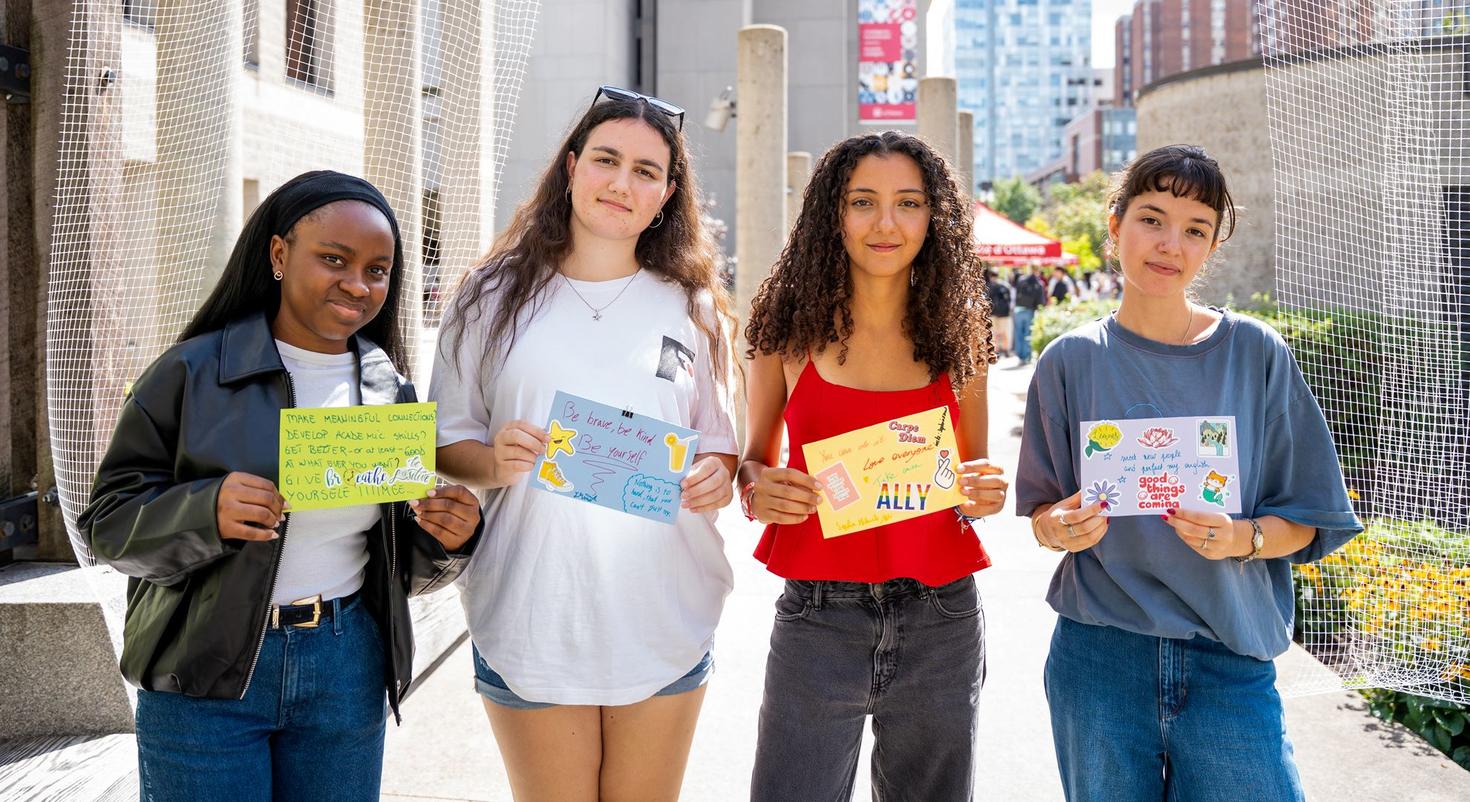 Four students who participated in the September 8 Dream Tree event hold up their artworks depicting their hopes and dreams.