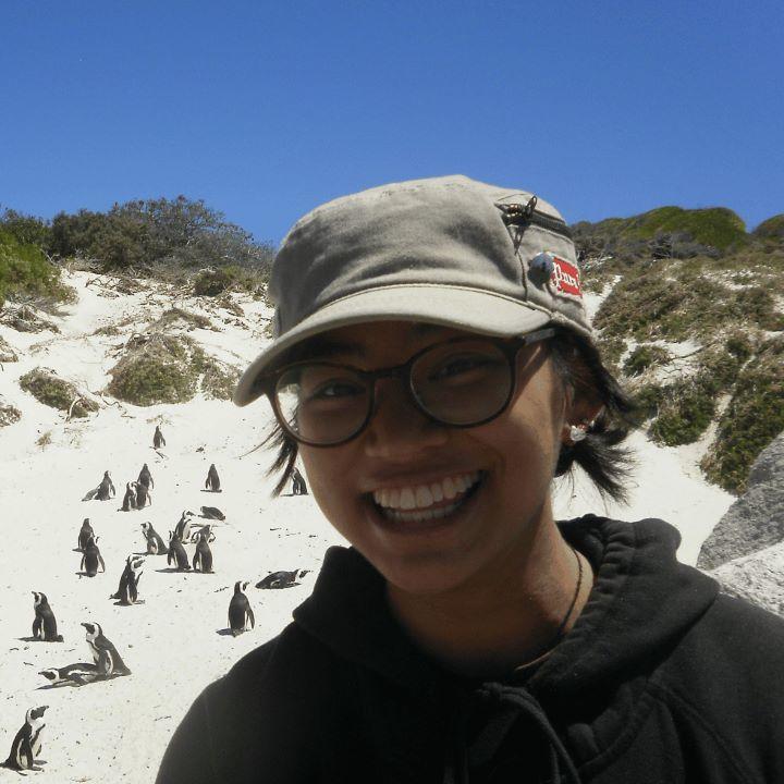 Megan Satumba on a beach in South Africa with penguins in the background.