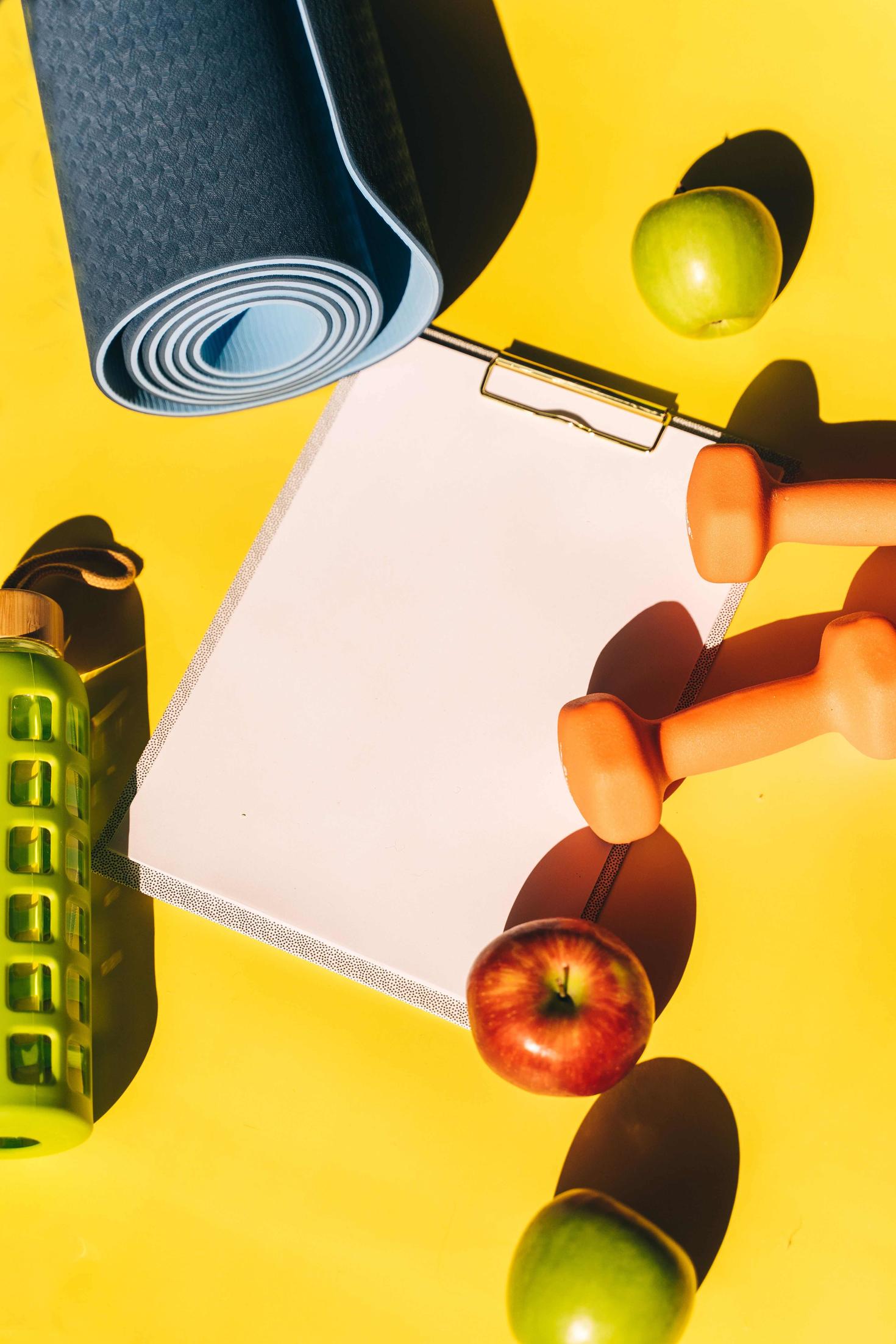 Yoga mat, apples, water bottle and a clipboard 