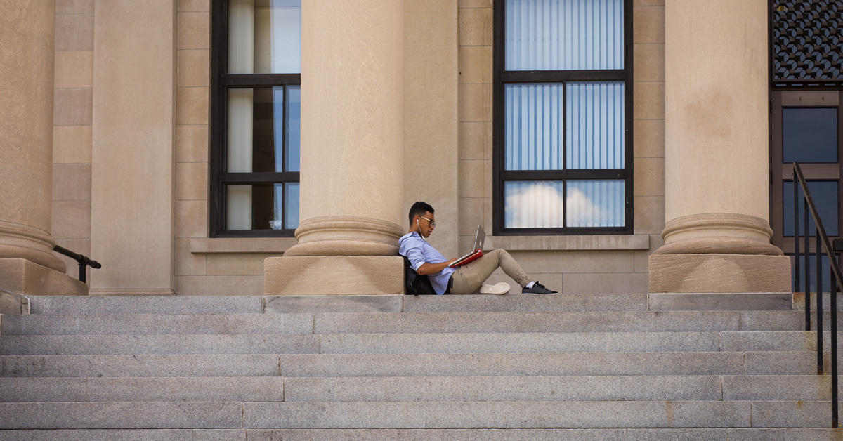 Un étudiant sur son ordinateur portable à l’extérieur du Pavillon Tabaret.