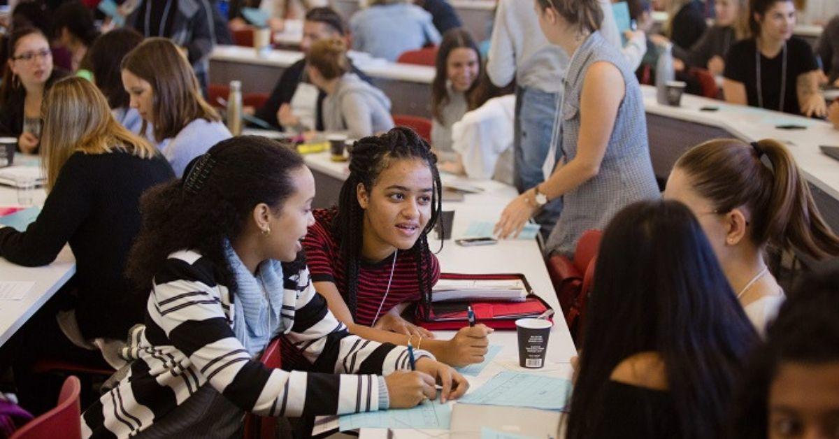 Des étudiantes jasent dans une salle de classes.