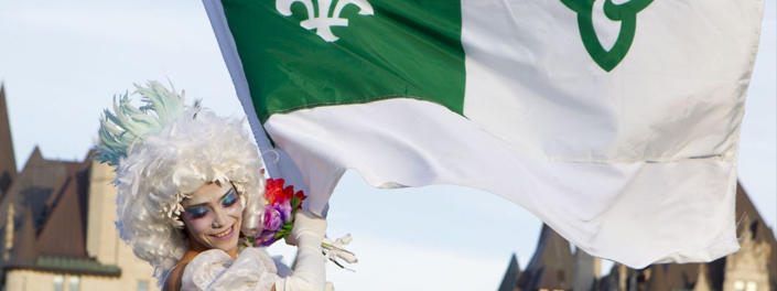 Jeune femme costumée tenant le drapeau franco-ontarien.