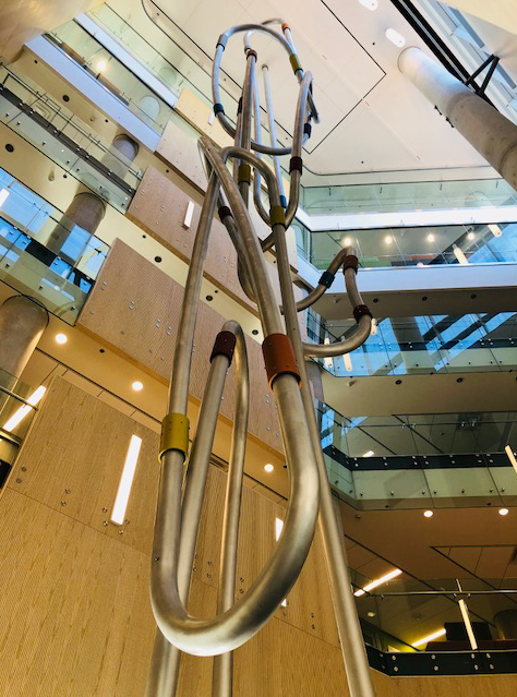 Structure de métal tubulaire fixée au sol et au plafond de l'édifice par un atrium traversant tous les étages.