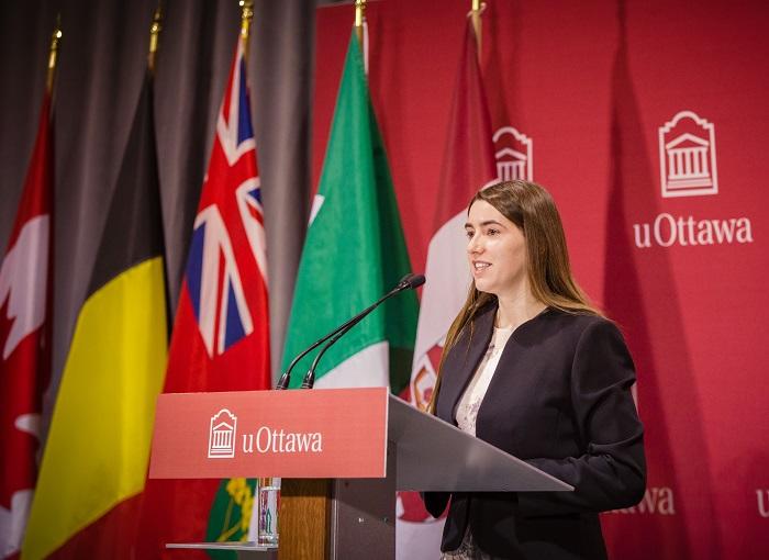 Émilie Cousineau parle au public sur le podium de la salle Huguette Labelle