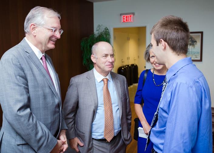 Two men and a woman chat with a student.