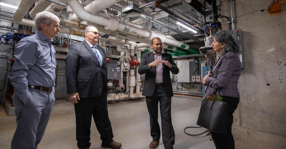 Le gestionnaire énergie et environnement de l'Université d'Ottawa, Faizal Sudoollah, parle à trois dirigeants d'Enbridge Gas dans une salle mécanique 
