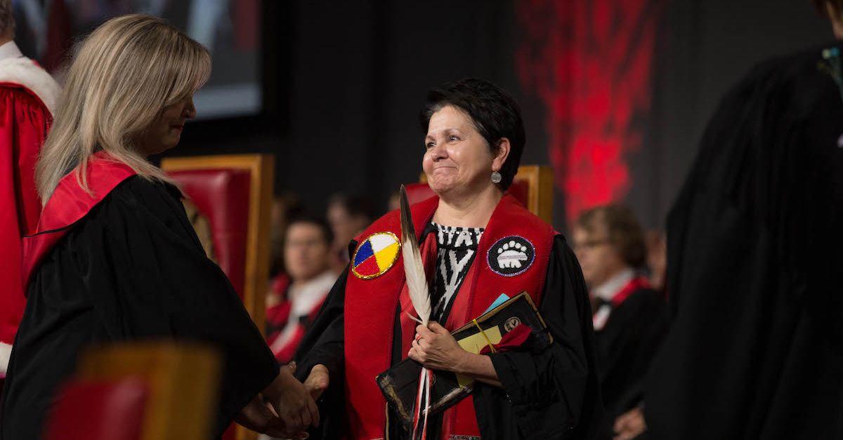 Étudiante vêtue d'une toge de graduation reçoit un diplôme à la collation des grades.