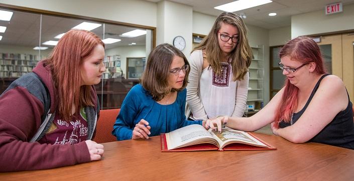 Four women look at a book together.