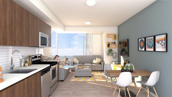 Une cuisine et un salon à aire ouverte. On y retrouve des électroménagers modernes et de larges fenêtres.