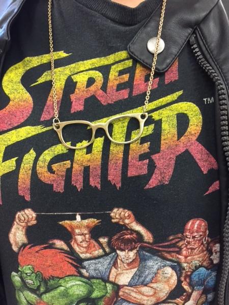 Un collier de lunettes miniatures sur un T-shirt de Street Fighter.